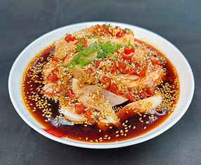 Sliced chicken in spicy red chili oil with sesame seeds and green onions.