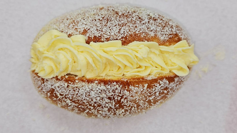 Delicious cream-filled donut with frosting on white textured background.
