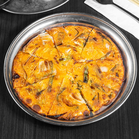 盘子里的韩国煎饼，切成片，配上餐具和木桌，美味佳肴