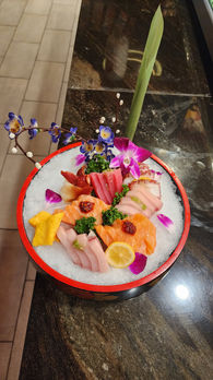 Sushi sashimi platter with floral arrangement and a lemon slice on ice
