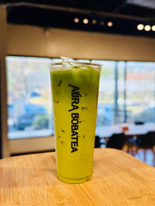 Iced matcha boba tea in a clear cup with Aura Bobatea text.