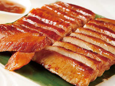 Sliced roasted duck with sauce, arranged on a green leaf plate.