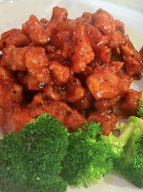 Delicious glazed orange chicken bites served with vibrant green broccoli.