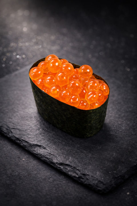 Sushi with bright orange fish eggs on a dark background, delicious food.