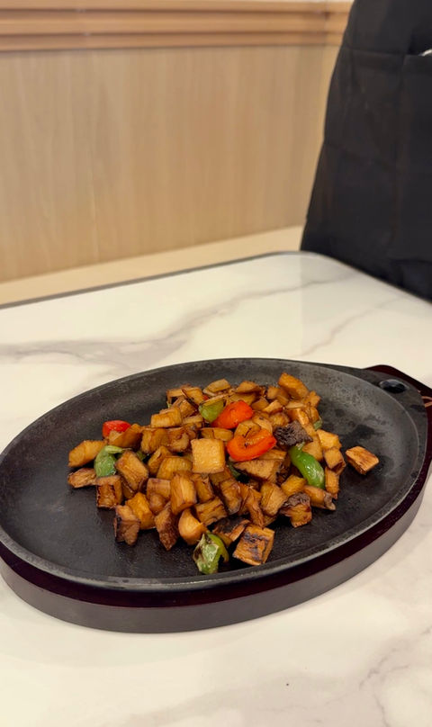 盘子里的炒菜，配有红辣椒和绿辣椒，在白色桌子上。