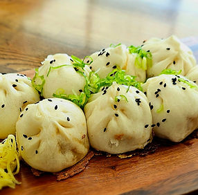 美味包子撒黑芝麻和葱花,置于木板上。