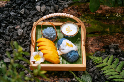 芒果糯米饭美食,芒果切片,蓝糯米饭和椰奶酱,置于木质托盘上