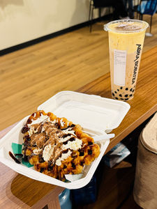 Waffle with toppings and boba tea from Aura Boba Tea, on the table.