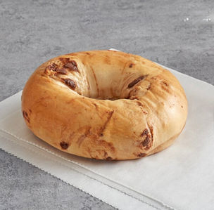 Freshly baked cinnamon raisin bagel on parchment paper, ready to eat.