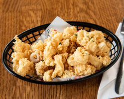 Fried calamari in a black basket on a wooden table, delicious food