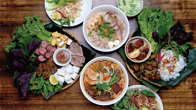 Variety of Vietnamese dishes with vegetables and meat on wooden table Gao Vietnamese Cuisine