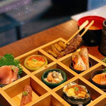 Wooden tray with assorted sushi, sauces, and skewers at restaurant sushi kashiwa