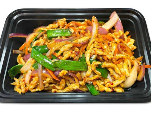 Chicken stir fry with vegetables in a black container on a white backdrop.