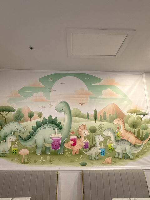 Dinosaur mural with various dinosaurs holding colorful drinks, sunny background, mountain view.