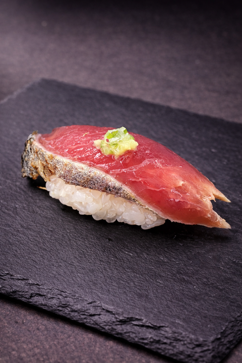 Raw tuna sushi on a black plate with wasabi, ready to eat.