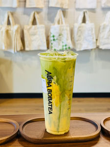 Aura Bobatea matcha latte in a clear cup on wooden tray, delicious drink