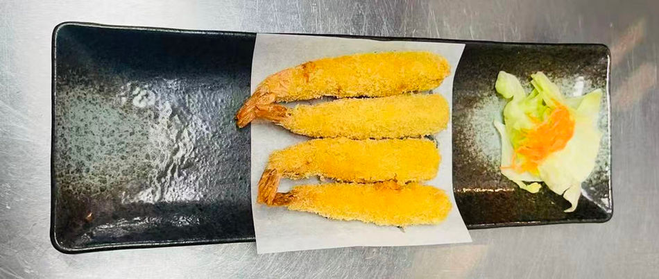 Four golden fried shrimp tempura on a black plate with small salad.
