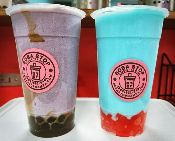两杯珍珠奶茶,蓝莓奶茶和蓝色奶茶,带有“Boba Stop”标签。