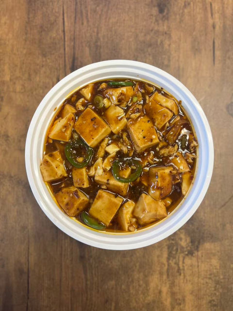 Delicious Mapo Tofu dish in a white bowl on a wooden table.