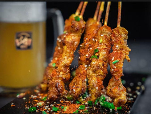Skewered meat with visible seasoning, Yang Sao 杨嫂炸串 and a beer glass.
