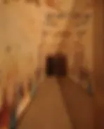 Narrow corridor with colorful ancient mural art to dark doorways.