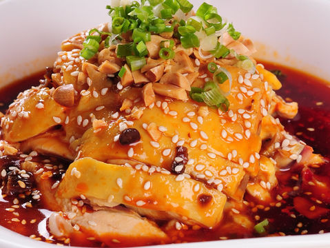 Delicious sesame chicken dish with peanuts and green onions in a bowl.