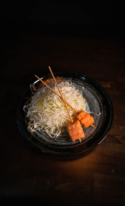 Plate with skewers of salmon and shredded cabbage on a wooden table.
