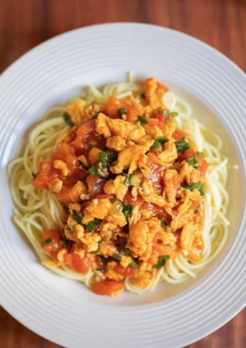 Pasta dish with tomato sauce and scrambled eggs on a white plate