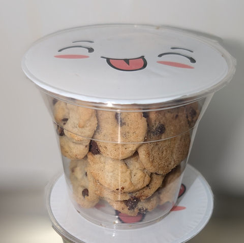 一杯装满巧克力饼干的透明杯子，带有可爱表情的盖子。