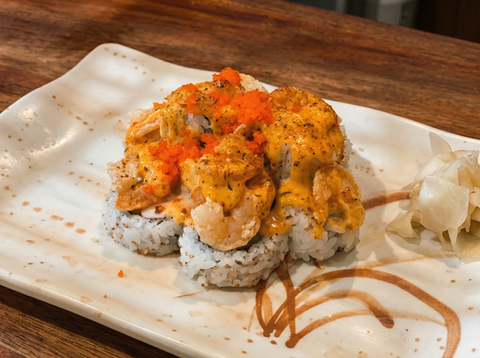 Sushi rolls topped with shrimp, creamy sauce, and roe