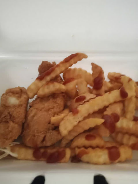 炸薯条和鸡块，配有番茄酱，放在一个白色容器中。美味的快餐