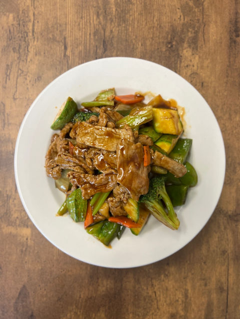 Plate of cooked meat and vegetables on a wooden table for dinner.