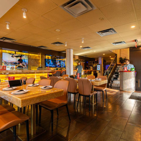 Interior view of a restaurant with tables, chairs, and a bar.