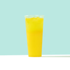 Tall glass of yellow juice on a blue and white background. 
