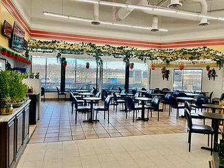 Restaurant interior with tables and chairs, decorative vines, and large windows with views.
