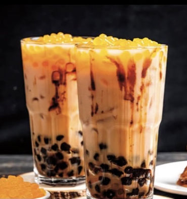 两杯珍珠奶茶特写,杯中满是珍珠和饮料,背景模糊。