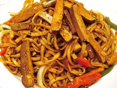 Delicious noodles dish with tofu and vegetables, served on a white plate