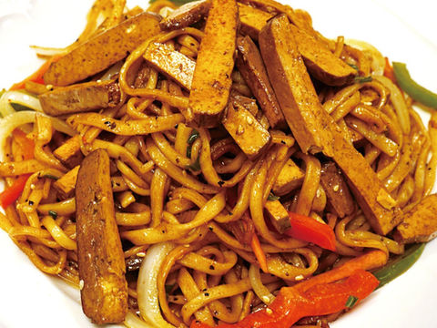 Delicious noodles dish with tofu and vegetables, served on a white plate