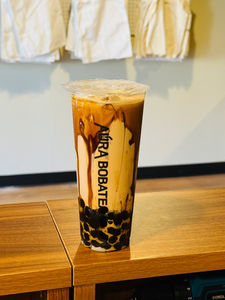 Aura Bobate drink with brown liquid and black boba on a table