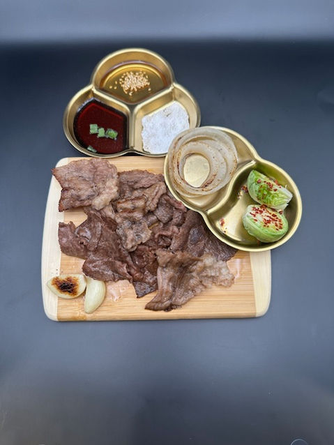 Cooked meat with dipping sauces, onions, and garlic