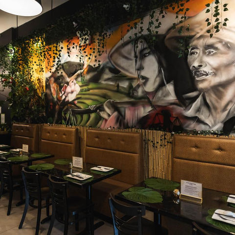 Restaurant interior with mural depicting people and tables with menus Just Pho You