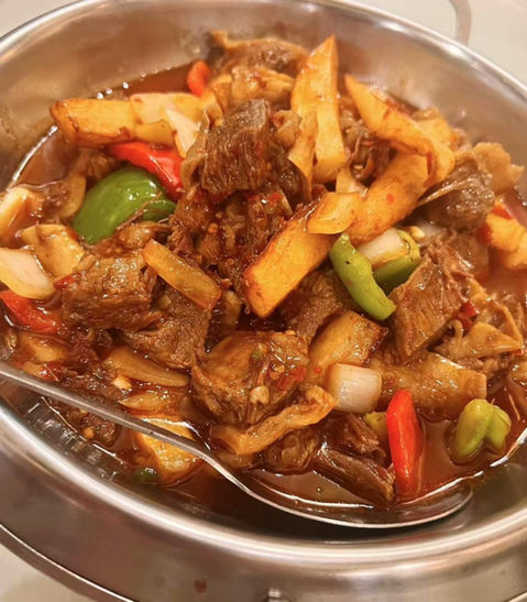 Savory beef stew with potatoes, peppers, and onions in serving dish.