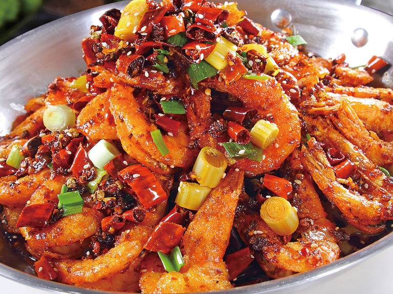 Close-up of spicy fried shrimp in a metal pan with red peppers.