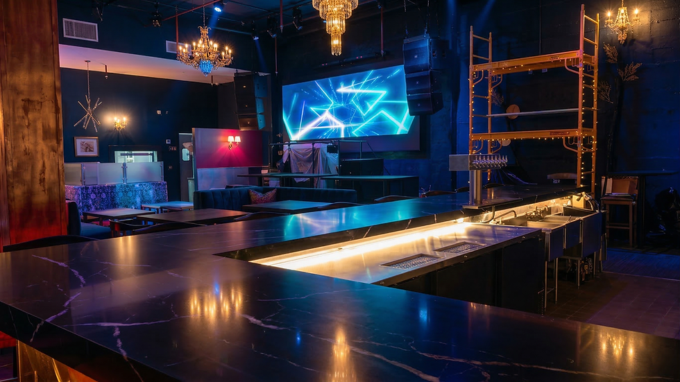 Luxurious nightclub bar with marble counter, chandeliers, and illuminated screen display.