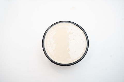 Overhead view of a black bowl filled with creamy white sauce.