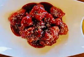 Sweet chili fried chicken pieces with sesame seeds, served on a plate.