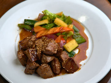 盘子里的牛肉和蔬菜，配上酱汁，美味可口的菜肴，准备食用。