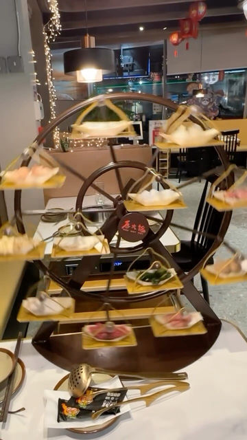 Wooden Ferris wheel display with hot pot ingredients, '天府热串串' restaurant.
