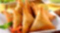 Golden brown crispy samosas served with red bell pepper and lemon.