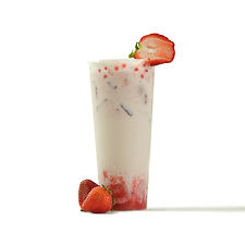 Strawberry milk tea with popping boba and fresh strawberries on white.